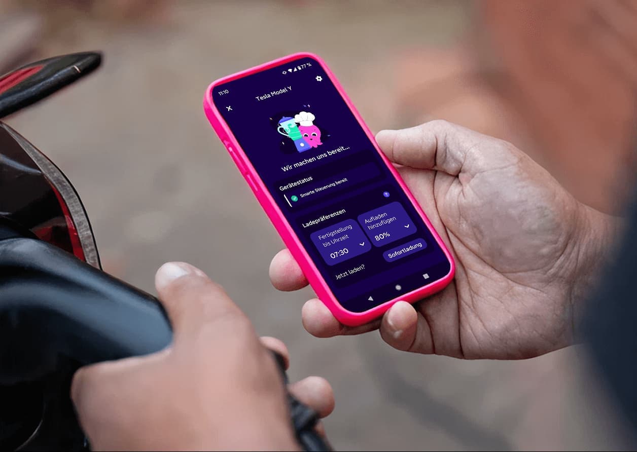 Eine Person lädt ein E-Auto und hat ein Handy mit der Octopus Energy App in der Hand