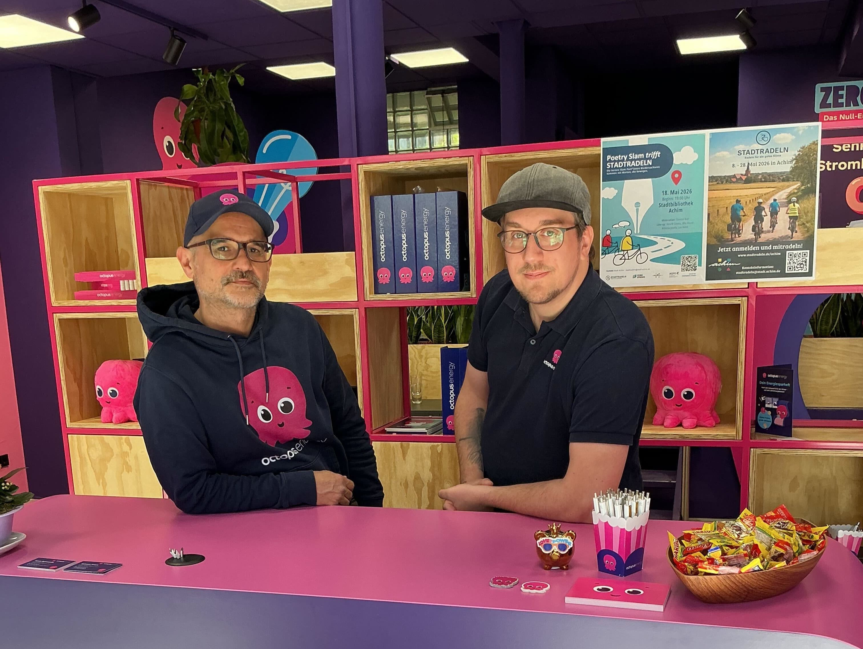 Zwei Octopus Energy Mitarbeiter lächeln in die Kamera