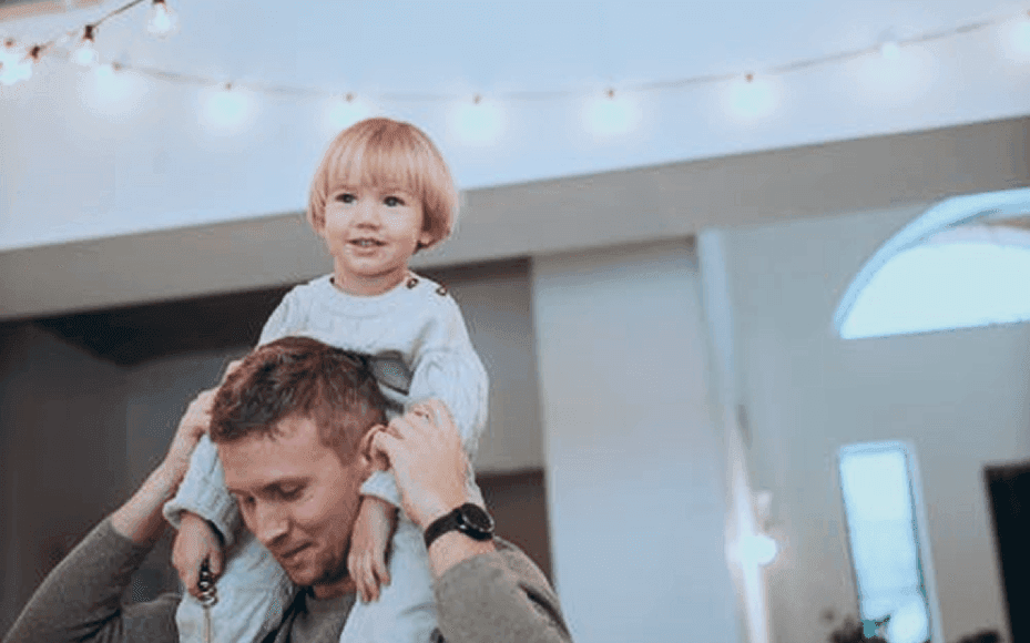 Ein Vater hat sein glückliches Kind auf den Schultern